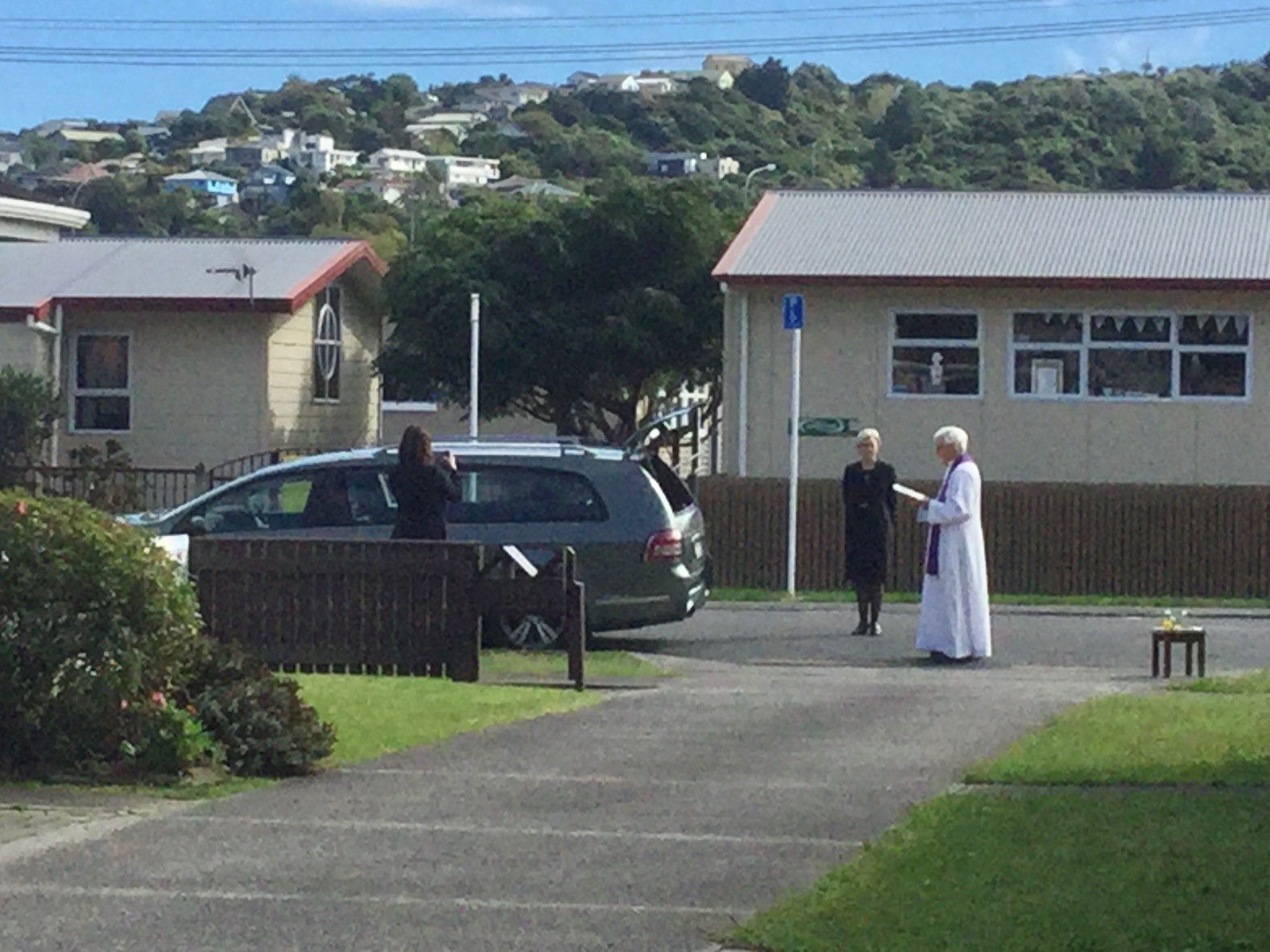 Fr Maurice Carmody praying by a hearse stopped outside is Plimmerton house5